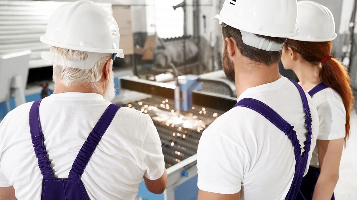 Работники производственного цеха смотрят на станок